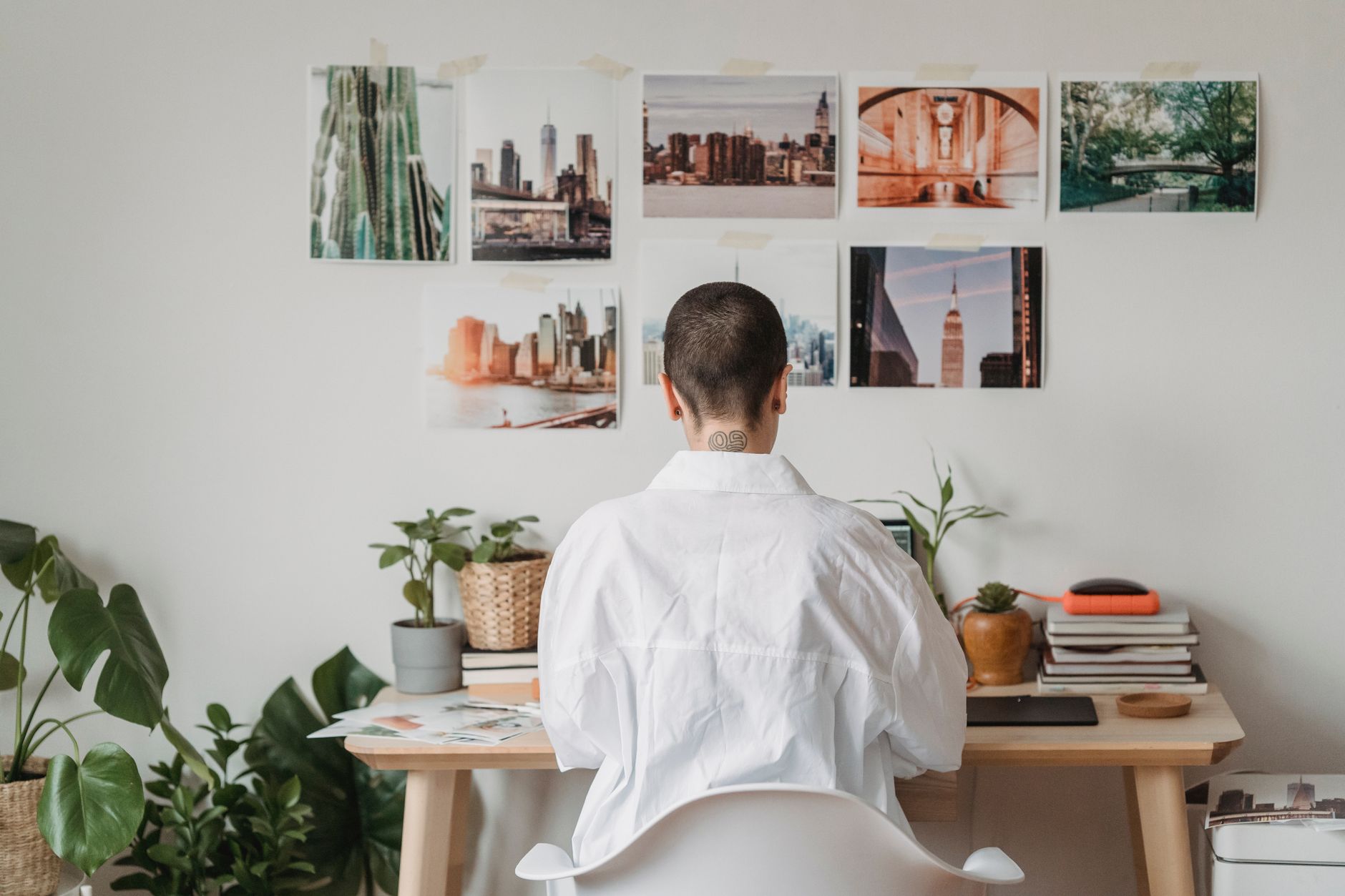 Vue de dos d'une freelance travaillant sur un ordinateur portable dans une pièce décorée de photos accrochées au mur.